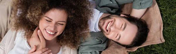 Top view of cheerful woman lying on happy boyfriend during picnic in summer park, banner — Fotografia de Stock