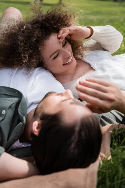 Cheerful woman lying with happy boyfriend during picnic in summer park — Stock Photo