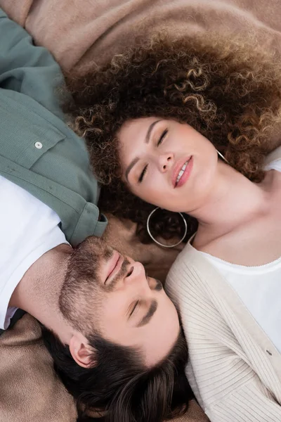 Vista dall'alto di felice giovane donna e uomo con gli occhi chiusi sdraiati su una morbida coperta — Foto stock