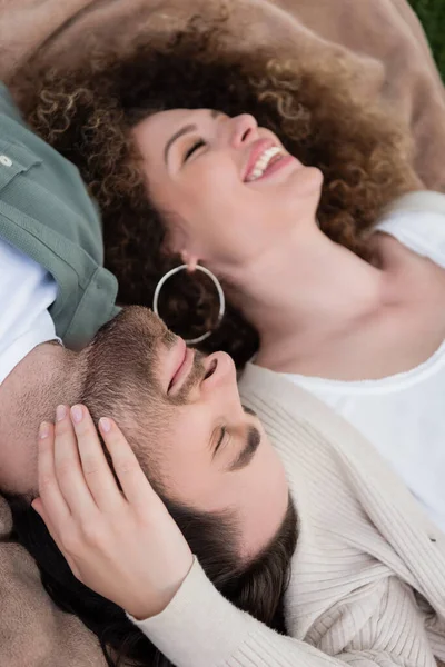 Top view of pleased young woman and man with closed eyes lying on soft blanket — Photo de stock