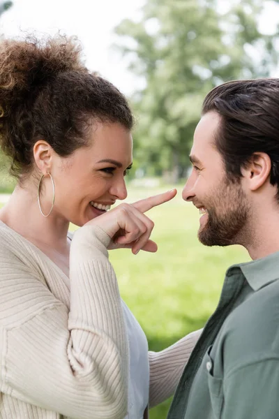 Щаслива кучерява жінка вказує пальцем на веселого хлопця — стокове фото