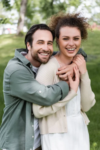 Portrait of positive young woman hugging curly woman in park — Stockfoto