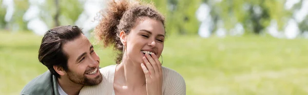 Felice uomo e donna allegra ridendo mentre copre la bocca nel parco, banner — Foto stock