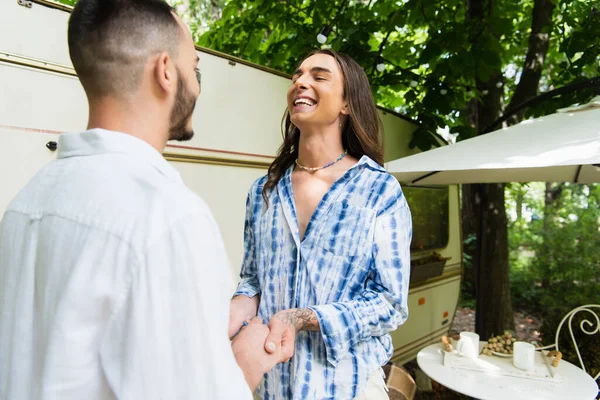 Happy tattooed gay man holding hands of bearded boyfriend near travel van — Stock Photo