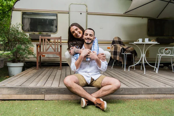 Happy tattooed gay man hugging cheerful boyfriend near travel van on yard — Fotografia de Stock