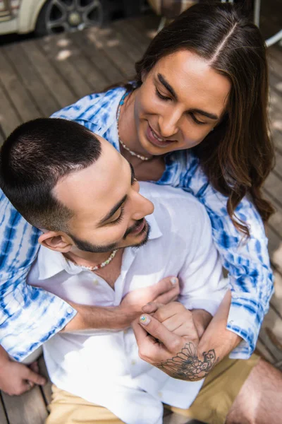 Alto ángulo vista de feliz tatuado gay hombre abrazando alegre novio - foto de stock