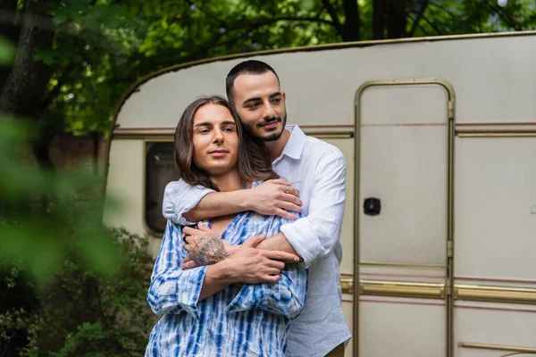 Bärtiger schwuler Mann umarmt tätowierten Freund in der Nähe von Reisebus — Stockfoto