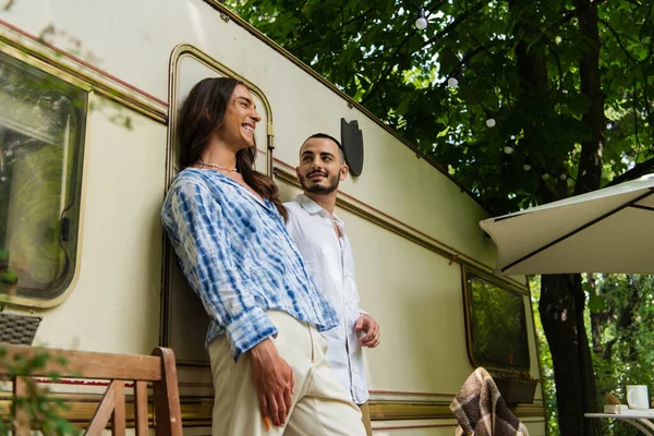 Blick auf ein glückliches homosexuelles Paar, das beim gemeinsamen Campen in der Nähe eines Lieferwagens steht — Stockfoto