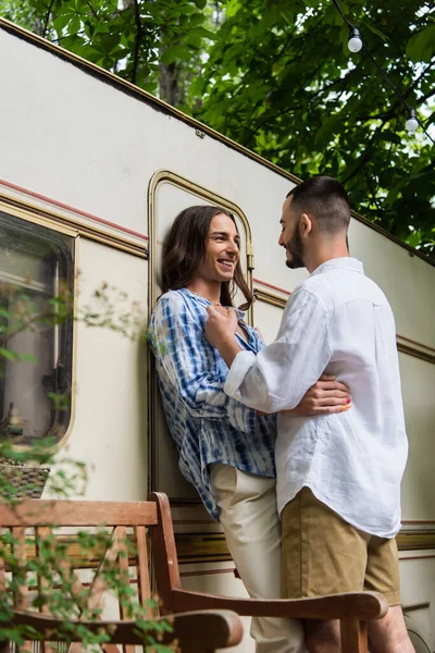 Happy gay couple smiling while hugging during journey near van — Stock Photo