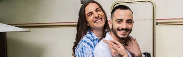 Happy gay couple smiling while hugging and looking at camera near van, banner — Stock Photo