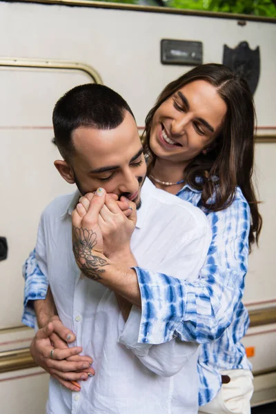 Happy gay man smiling while hugging and looking at bearded boyfriend near van — Stock Photo