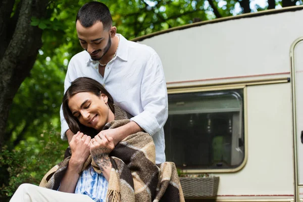 Happy bearded man hugging tattooed husband with golden wedding ring near van — Stock Photo