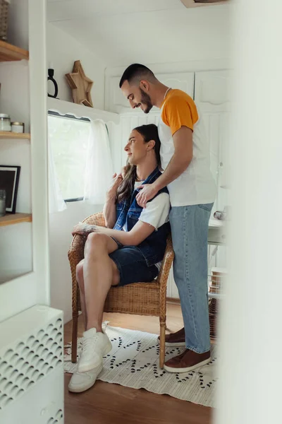 Gay hombre sentado en sillón cerca barbudo novio en van - foto de stock