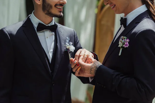 Cropped view of happy gay man wearing wedding ring on finger of cheerful groom — Stock Photo