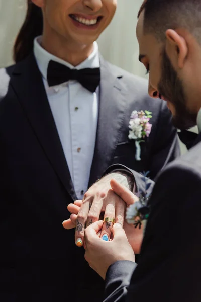 Bearded gay man wearing wedding ring on finger of happy tattooed groom — Photo de stock