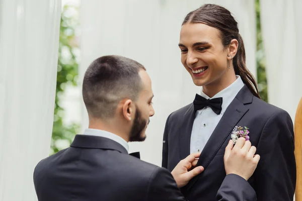 Homosexuell Mann Anpassung boutonniere auf Anzug von glücklich bärtigen Bräutigam — Stockfoto