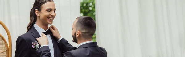 Gay hombre ajuste lazo en traje de feliz novio en formal desgaste, bandera - foto de stock