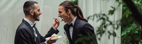 Glücklich Homosexuell Mann in formeller Kleidung Fütterung Ehemann mit Hochzeitstorte, Banner — Stockfoto