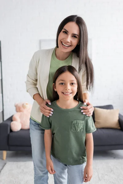 Femme heureuse debout derrière un enfant souriant dans le salon — Photo de stock