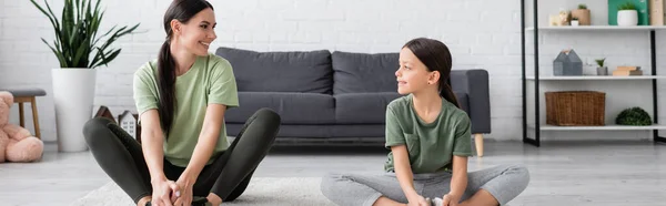 Babysitter and girl sitting in fire log pose and smiling at each other, banner — Stock Photo