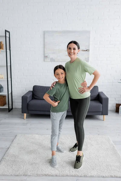 Comprimento total de feliz babá e criança em sportswear abraçando e olhando para a câmera — Fotografia de Stock