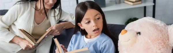 Mädchen liest Buch zu Teddybär in der Nähe Babysitter auf Hintergrund, Banner — Stockfoto