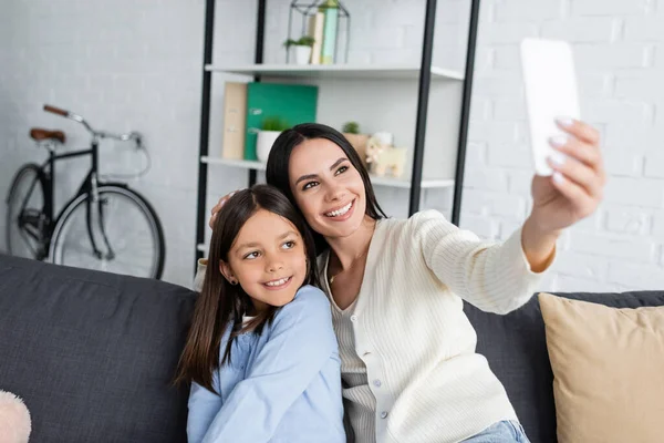 Lächeln Babysitter Selfie auf dem Handy mit Mädchen auf dem Sofa zu Hause — Stockfoto