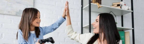 KIEW, UKRAINE - 23. MAI 2022: glückliches Mädchen mit Steuerknüppel gibt Kindermädchen High Five, Banner — Stockfoto