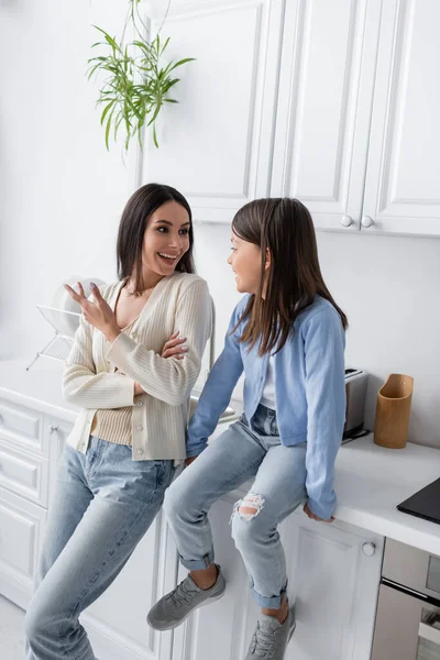 Babá alegre falando com a menina sentada na bancada na cozinha — Fotografia de Stock