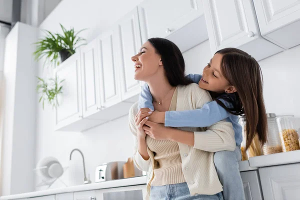 Felice ragazza abbracciare ridere babysitter in cucina — Foto stock