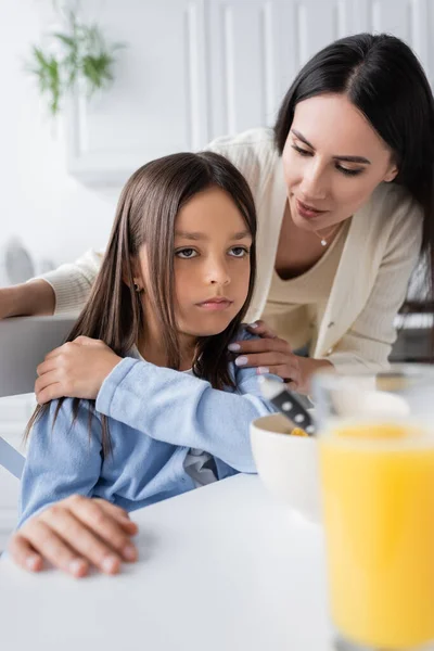 Kindermädchen spricht mit beleidigtem Mädchen in der Nähe des Frühstücks auf verschwommenem Vordergrund — Stockfoto