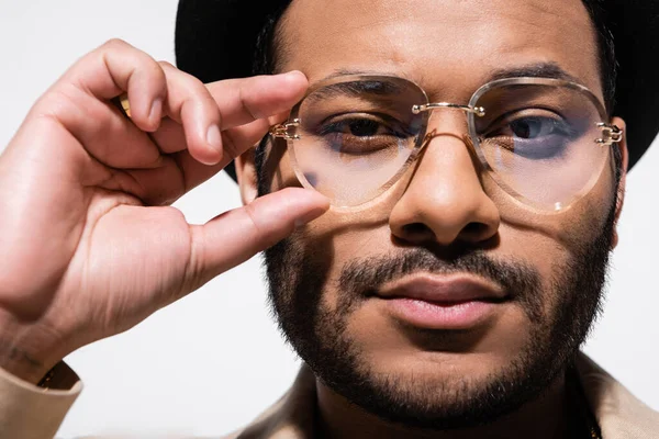 Gros plan de l'artiste hip hop indien barbu en chapeau fedora ajustant les lunettes isolées sur gris — Photo de stock