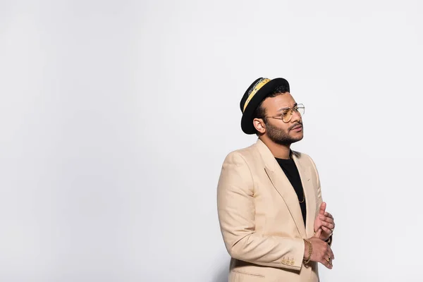 Bearded indian hip hop singer in fedora hat and eyeglasses isolated on grey — Stock Photo