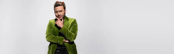 Pensive eastern hip hop performer in green velvet blazer and crown isolated on grey, banner — Fotografia de Stock