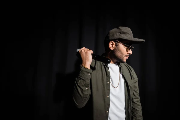 Hip-Hop-Performer mit Sonnenbrille hält Mikrofon auf schwarz — Stockfoto