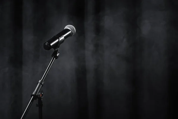 Microphone on stand on black stage with curtain and smoke — Stock Photo