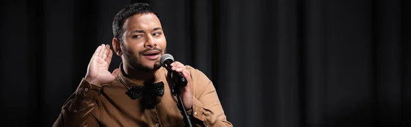 Indian comedian listening and performing stand up comedy into microphone on black with smoke, banner — Stock Photo