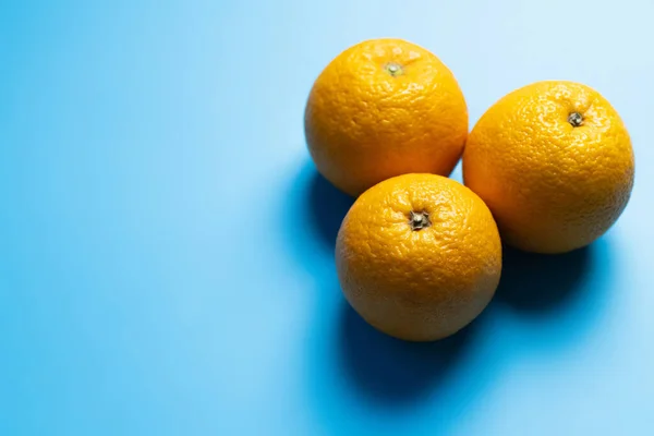 Draufsicht auf Orangen auf blauem Hintergrund mit Schatten — Stockfoto