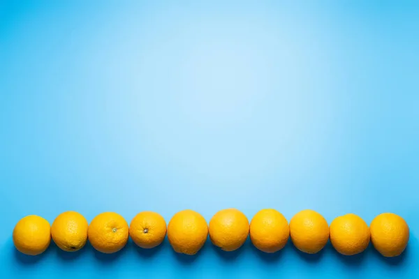 Flat lay with row from oranges on blue background — Fotografia de Stock