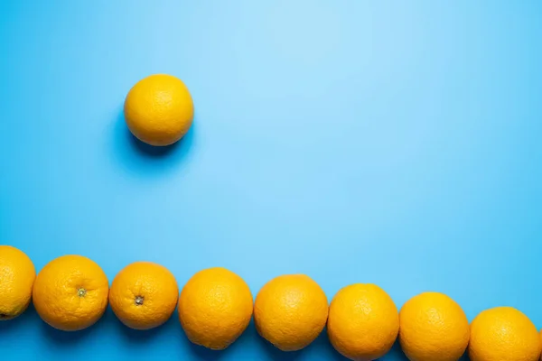 Colocación plana con naranjas con sombra sobre superficie azul - foto de stock