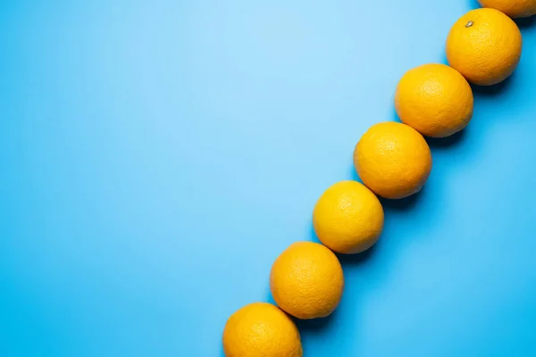 Top view of row of oranges on blue background with copy space — Fotografia de Stock