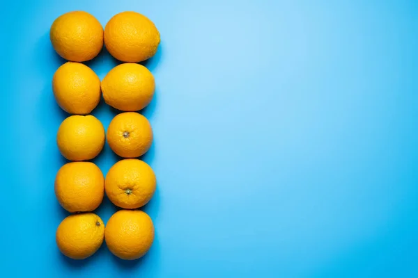 Плоская укладка органических апельсинов на голубом фоне — стоковое фото