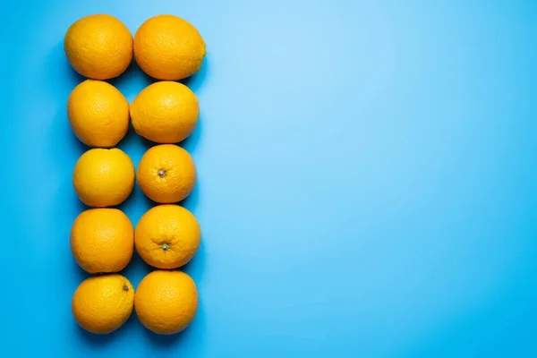 Flat lay of organic oranges on blue background — Fotografia de Stock