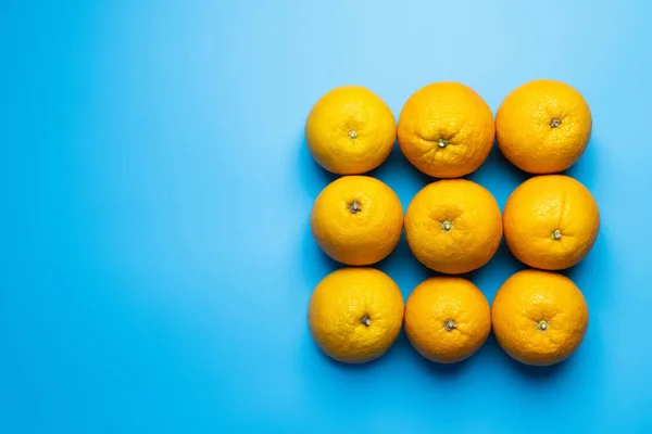 Colocación plana con naranjas en forma cuadrada sobre fondo azul - foto de stock