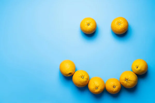 Flat lay with oranges in smile shape on blue background — Fotografia de Stock