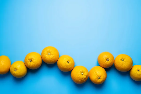 Pose plate avec des oranges naturelles sur fond bleu — Photo de stock