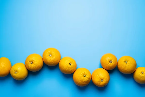 Flat lay with natural oranges on blue background — Fotografia de Stock