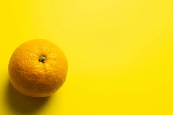 Top view of orange with shadow on yellow background — Stock Photo