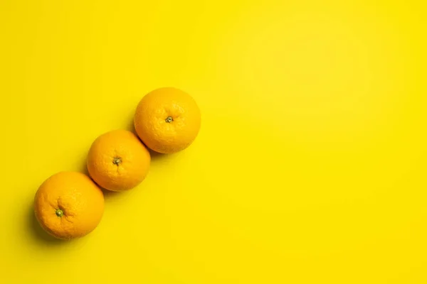 Top view of fresh oranges on yellow background — Stock Photo