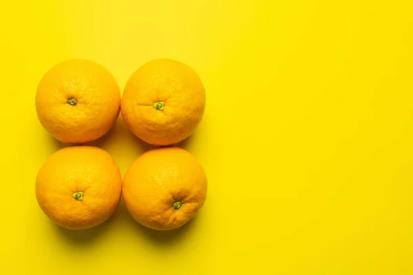 Pose plate avec des oranges mûres avec ombre sur fond jaune — Photo de stock